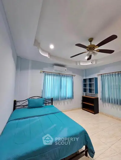 Spacious bedroom with modern ceiling fan and natural light, perfect for comfort and relaxation.