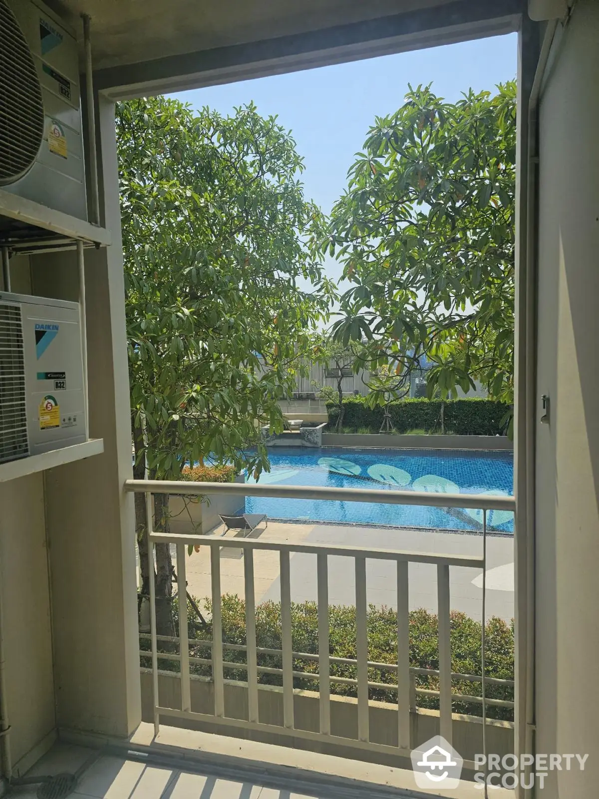 Stunning pool view from balcony with lush greenery and serene atmosphere