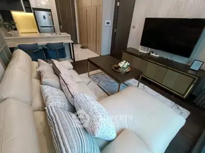 Modern living room with plush white sofa, sleek TV unit, and stylish kitchen bar area.