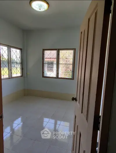 Bright empty room with tiled floor and large windows, perfect for customization.