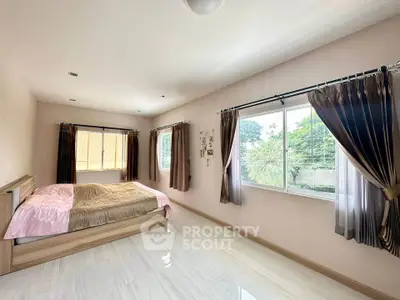 Spacious bedroom with large windows and elegant curtains, offering a serene garden view.