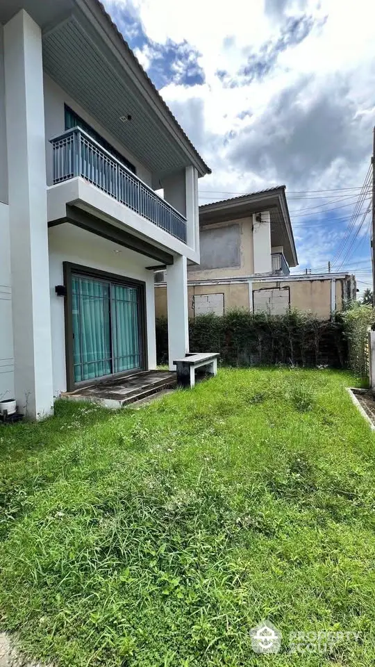 Modern two-story house with lush green garden and balcony