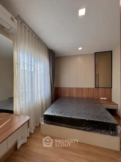 Modern bedroom with large window, wooden flooring, and sleek furniture design.