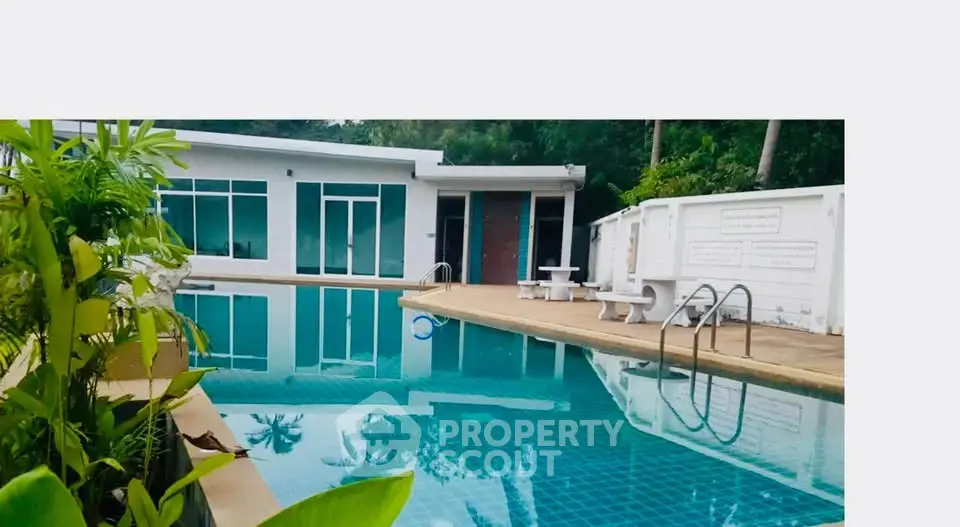 Luxurious poolside view of modern villa with lush greenery and sleek architecture.