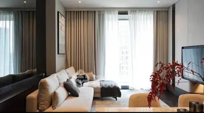 Modern living room with stylish sofa, large TV, and elegant curtains.