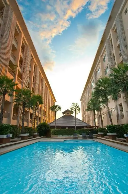 Stunning apartment complex with inviting pool and palm trees at sunset.