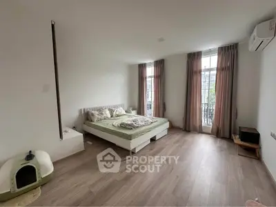 Spacious bedroom with large windows and modern decor in a stylish apartment.
