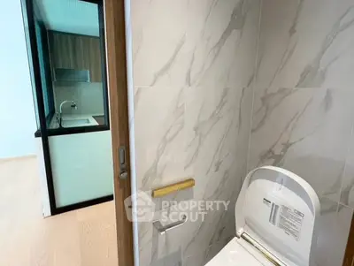 Modern bathroom with sleek design and partial view of adjacent kitchen area.