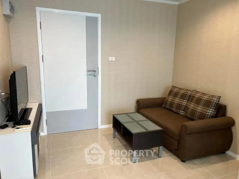 Cozy living room with modern sofa and flat-screen TV, perfect for relaxation.