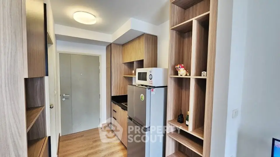 Modern kitchen with sleek wooden cabinetry and stainless steel appliances in a compact layout.