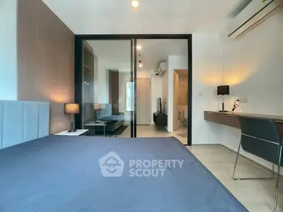 Modern bedroom with glass partition, stylish desk, and cozy lighting in a contemporary apartment.