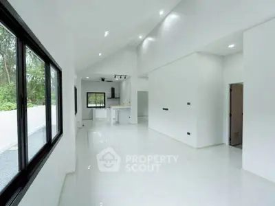Spacious modern living room with open layout and large windows offering natural light and serene views.