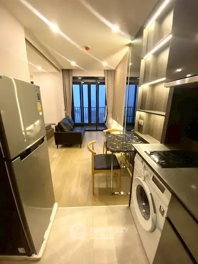 Modern open kitchen with sleek appliances and cozy living area, featuring a washing machine and stylish decor.