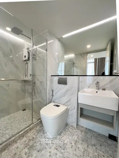 Modern bathroom with sleek design, featuring a glass shower enclosure and contemporary fixtures.