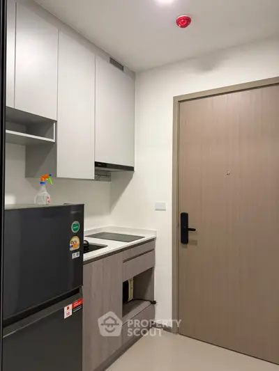 Modern compact kitchen with sleek cabinetry and integrated appliances in a stylish apartment.