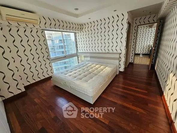 Spacious bedroom with modern design and large windows offering city views.