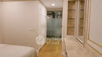 Cozy bedroom with built-in wardrobe and wooden flooring, leading to a modern en-suite bathroom, perfect for urban living.