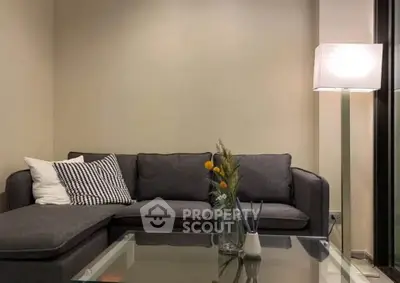 Modern living room with stylish gray sofa and glass coffee table, perfect for cozy relaxation.