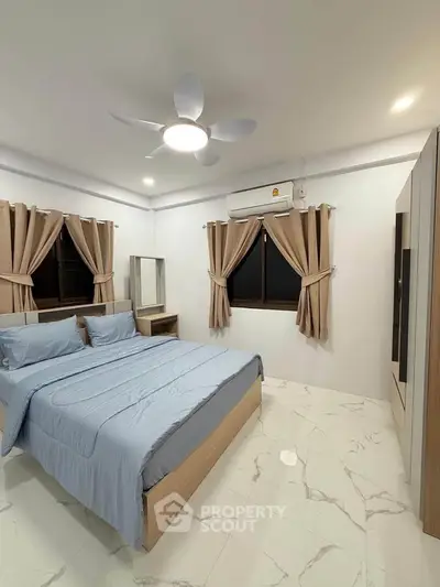 Spacious bedroom with modern decor and ample natural light, featuring a comfortable bed and stylish furnishings.