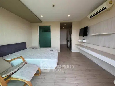 Modern studio apartment with sleek design, featuring a cozy bed, wall-mounted TV, and air conditioning.