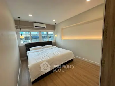 Modern bedroom with large bed and ambient lighting, featuring wooden flooring and city view.