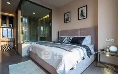Chic modern bedroom with en-suite glass-walled bathroom, plush bedding, and stylish decor, perfect for urban living.