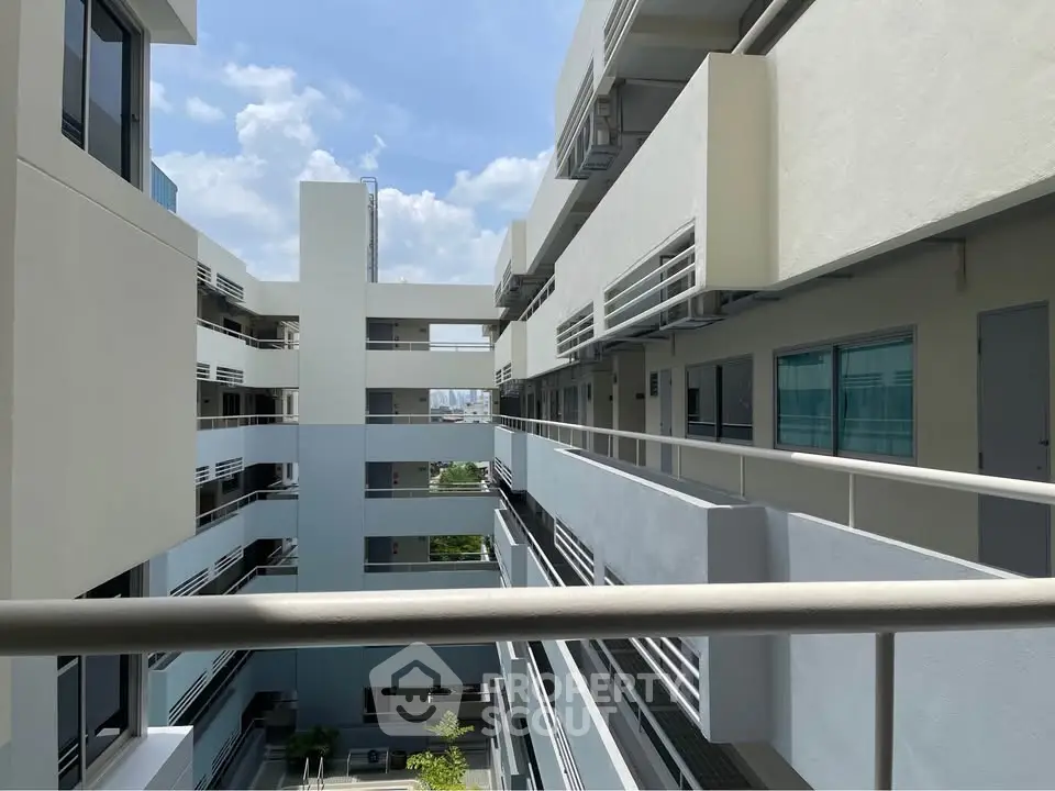 Modern apartment building with sleek design and spacious balconies under a clear blue sky.