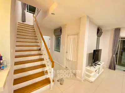 Modern interior with staircase and cozy living area featuring a TV setup, ideal for family gatherings.