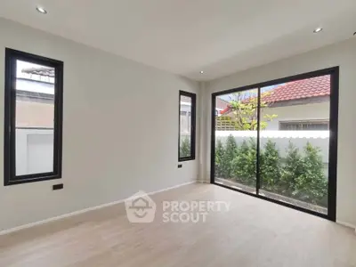 Spacious empty room with large windows and garden view, perfect for customization.