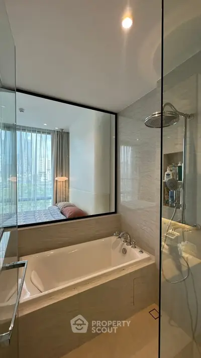 Luxurious bathroom with bathtub and glass shower, featuring a view into a modern bedroom.