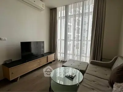 Modern living room with sleek furniture and large window offering natural light.