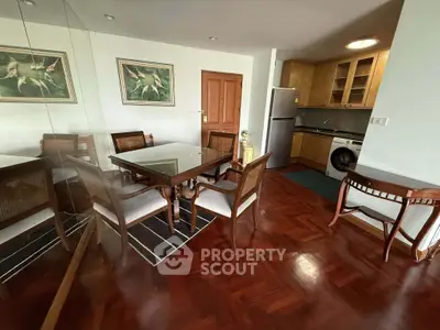 Charming dining area with wooden flooring and modern kitchen appliances in a cozy apartment.