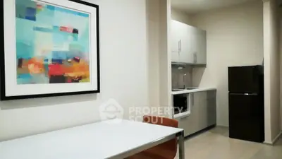 Modern kitchen with sleek cabinets and colorful wall art in a cozy apartment.