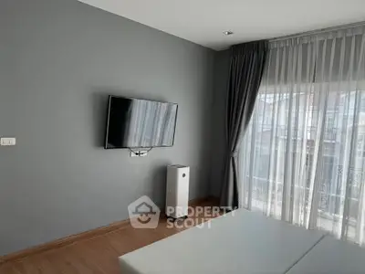 Modern living room with wall-mounted TV and large window with sheer curtains