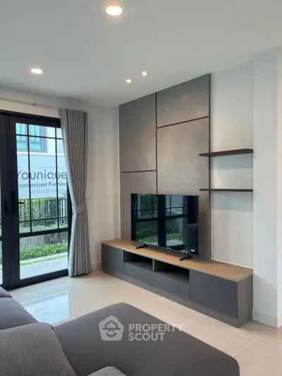 Modern living room with sleek TV unit and large window view.