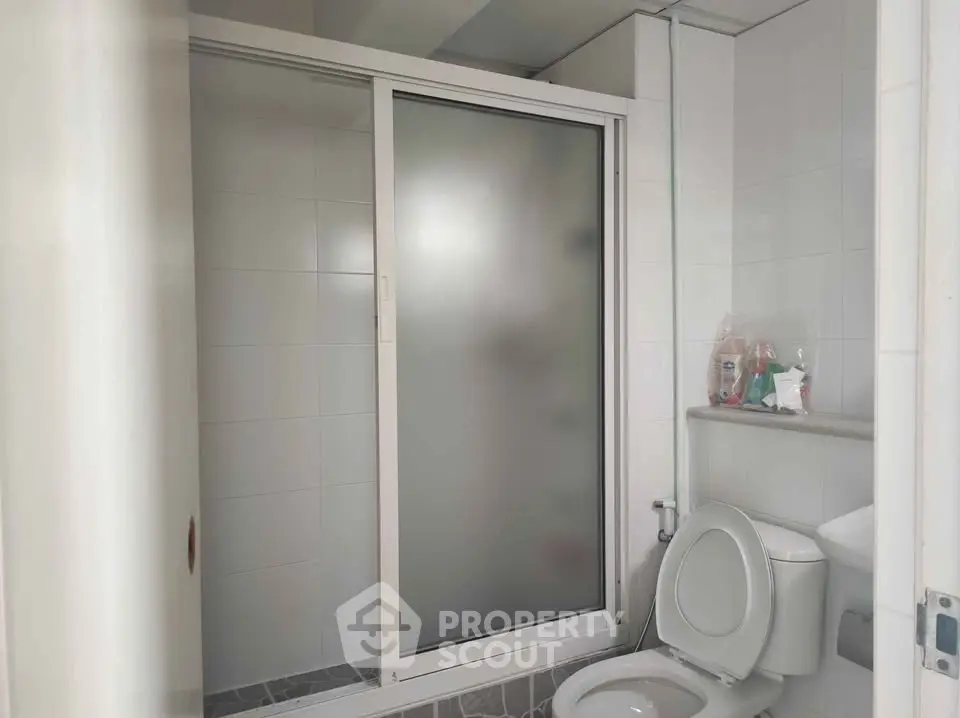 Modern bathroom with frosted glass shower and white tiles, ideal for contemporary living.