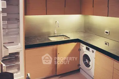 Modern kitchen with sleek cabinetry, built-in washing machine, and open fridge showcasing contemporary design.