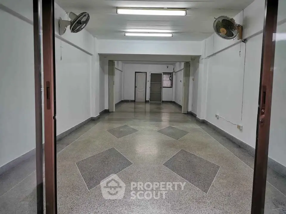 Spacious empty room with tiled floor and ceiling fans, ideal for customization.