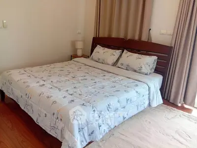 Cozy bedroom with wooden bed frame and floral bedding in a serene setting.