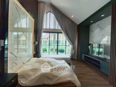 Luxurious bedroom with high ceilings and large windows offering natural light and elegant decor.