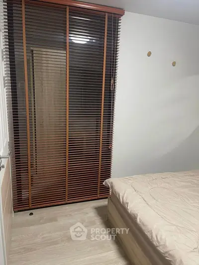 Cozy bedroom with modern blinds and wooden flooring, perfect for a peaceful retreat.