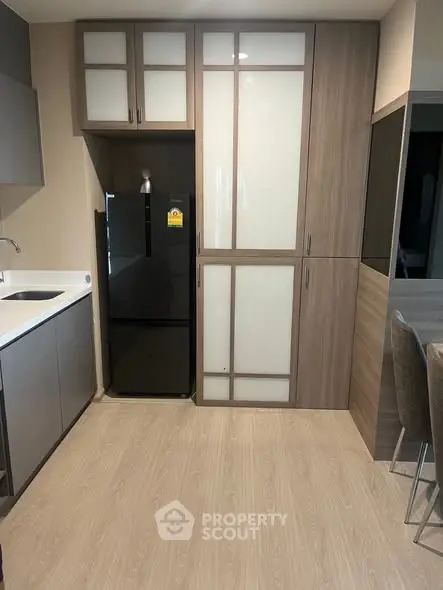 Modern kitchen with sleek cabinetry and black fridge in a compact layout.