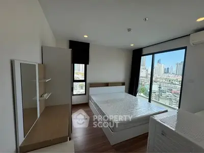 Modern bedroom with city view and natural light, featuring sleek furniture and large windows.