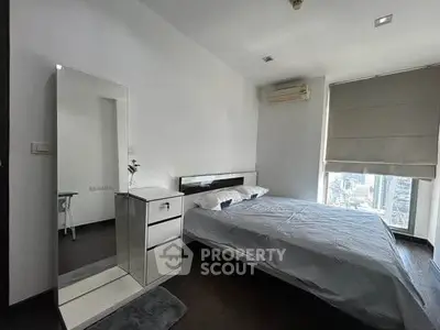 Modern bedroom with city view, featuring sleek furniture and large window for natural light.
