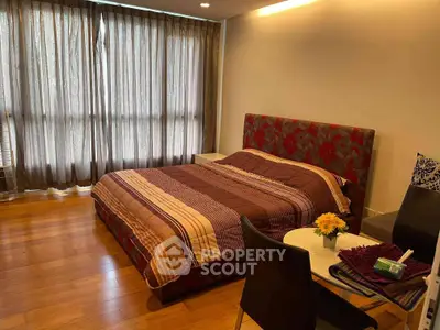 Spacious bedroom with elegant decor and natural light in modern apartment.