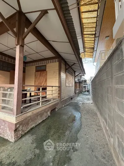 Charming rustic exterior of a traditional wooden house with covered porch and narrow alleyway.