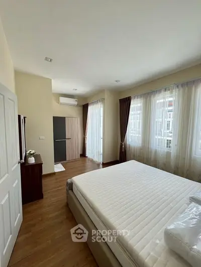 Spacious bedroom with large windows and modern furnishings, perfect for comfortable living.