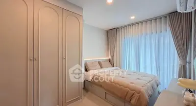 Cozy bedroom with elegant wardrobe and large window draped with sheer curtains, offering a serene ambiance.