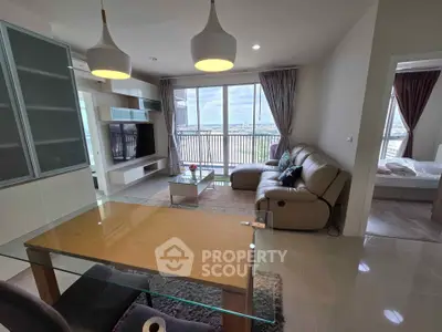 Spacious modern living room with large windows and city view, featuring stylish furniture and open layout.
