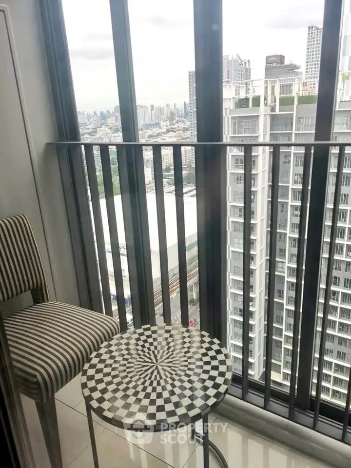 Stylish balcony with city view, featuring chic striped chair and checkered table, perfect for urban living.